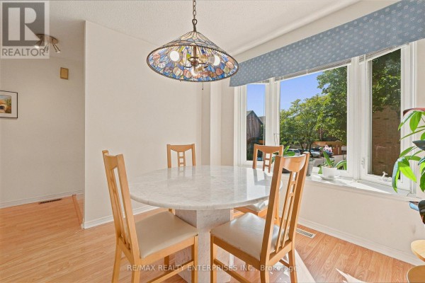 Dining room with a marble table, wooden chairs, and a large bay window with a street view. - 68 - 4635 Regents Terrace, Mississauga