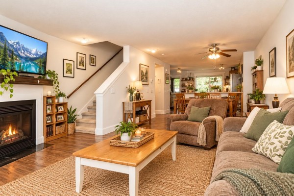 Living room fireplace, staircase, and view into dining area and kitchen. - 68 19250 65 Avenue, Surrey