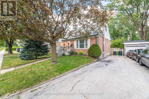 View of the front of a brick house with a driveway, trees, and parked cars. - 68 Allenby Avenue, Toronto