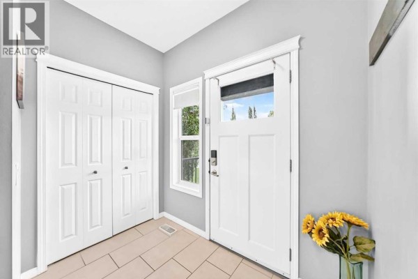 Interior entryway with a white front door, two white bi-fold closets, and cream-colored floor tiles. - 68 Belgian Street, Cochrane