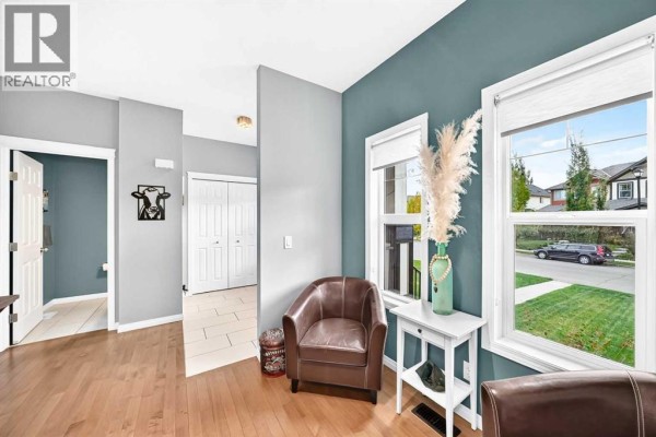 Living area with teal accent wall, two windows overlooking the street, a brown leather armchair, and a white side table. - 68 Belgian Street, Cochrane