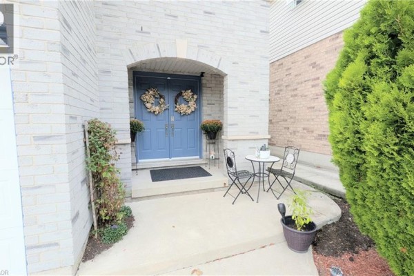 Covered front porch with blue double doors, two wreaths, and a small bistro set. - 68 Benjamin Drive, Hamilton