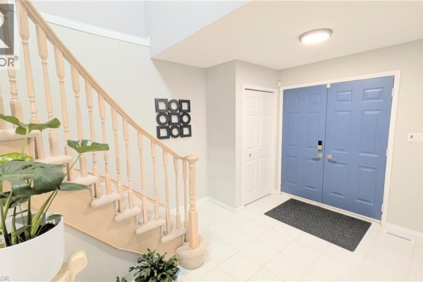 Foyer with white tile floor, a wooden staircase, and light blue double doors. - 68 Benjamin Drive, Hamilton