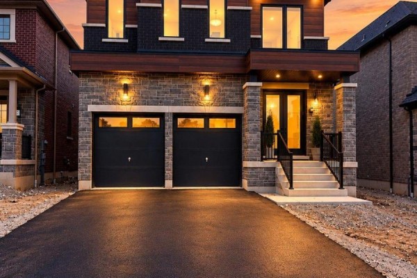 Modern home exterior at dusk with illuminated windows and a two-car garage. - 68 Caddie Crescent, Vaughan