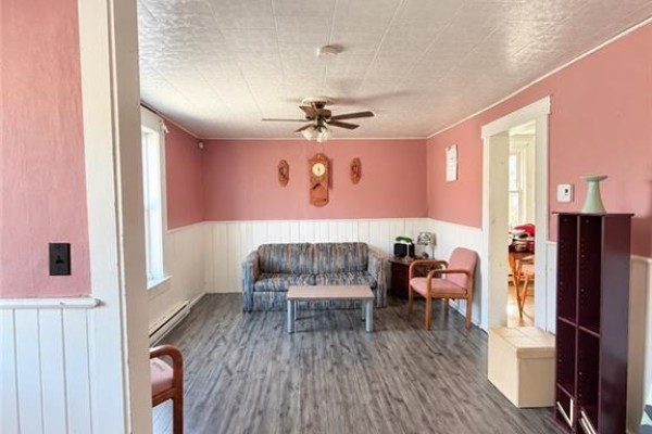 Living room with pink walls, wainscoting, sofa, and coffee table. - 68 Cunard, Miramichi