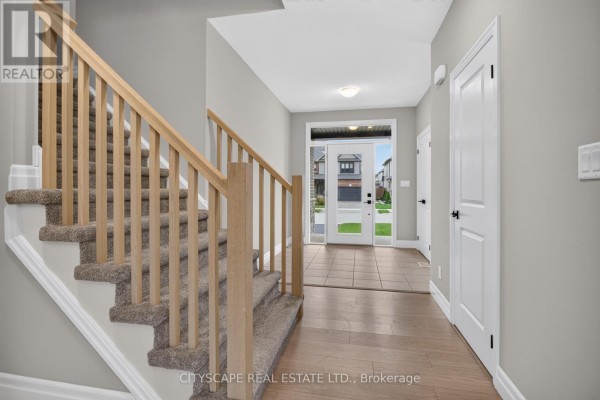 Interior foyer with carpeted stairs, hardwood floors, and view to the front door. - 68 Davidson Drive W, Stratford