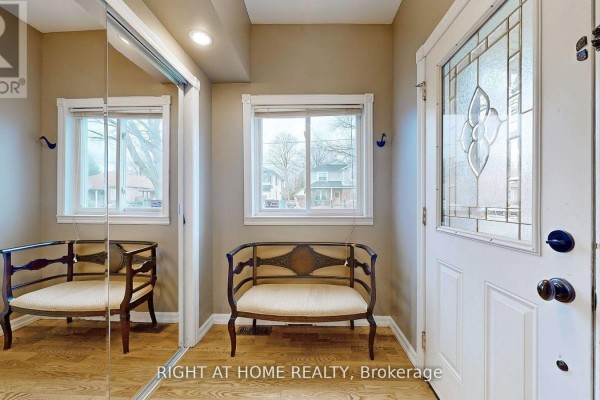 Entryway bench with ornate wood frame and upholstered seat, reflecting in a mirrored closet. - 68 Eaglewood Boulevard E, Mississauga