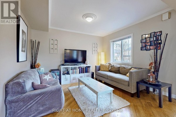 Living room with two sofas, a television, coffee table, and hardwood floors. - 68 Eaglewood Boulevard E, Mississauga