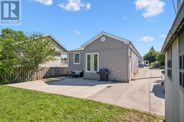 Back of the bungalow with a concrete patio, outdoor furniture, barbecue, and a driveway leading away. - 68 Elgin Street S, Cambridge