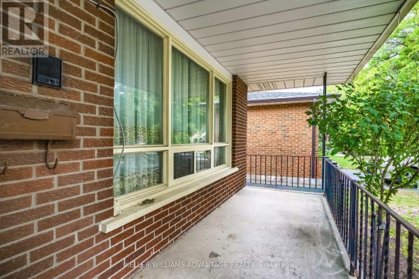 Close-up of the brick exterior with a covered porch, white railings, and window. - 68 Fullerton Crescent, Markham