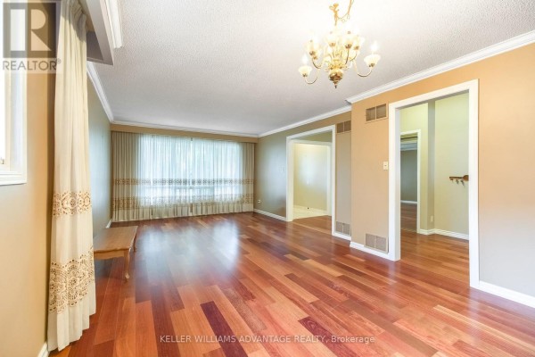 Living room with hardwood floors, beige walls, large window with drapes, and chandelier. - 68 Fullerton Crescent, Markham