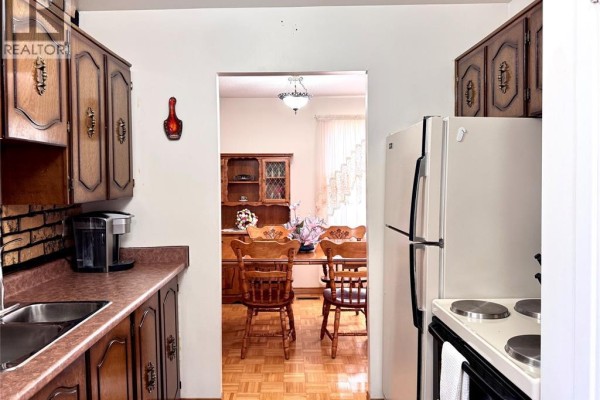 Kitchen with wood cabinets, stove, fridge, and view to dining room with wood table and chairs - 68 Greenbriar Trail Wallaceburg