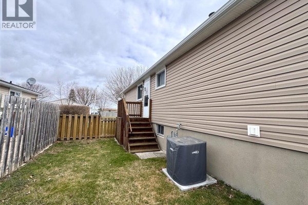 Backyard with vinyl siding, wooden fence, deck stairs, and AC unit - 68 Greenbriar Trail Wallaceburg
