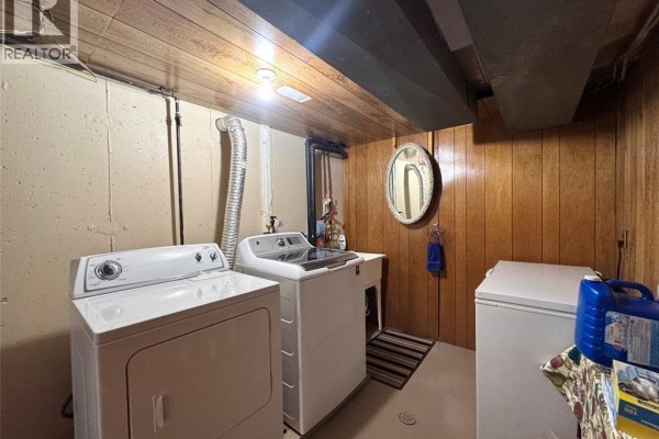 Washer, dryer, and freezer in laundry room with wood paneling - 68 Greenbriar Trail Wallaceburg