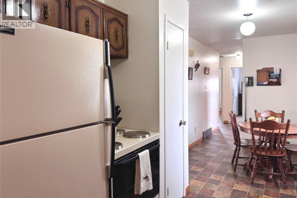 Kitchen with refrigerator, stove, wooden cabinets, and dining set - 68 Greenbriar Trail Wallaceburg