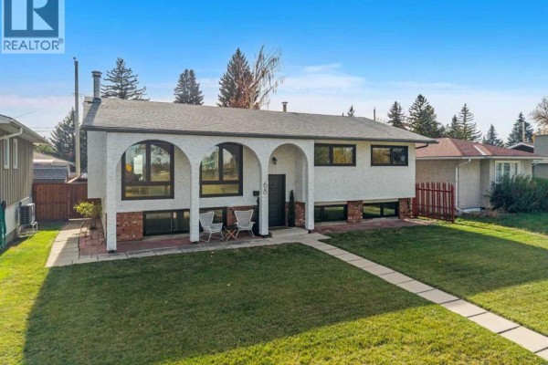 Close-up exterior view of the front entrance of a white split-level house with arched windows. - 68 Lake Emerald Road Se, Calgary