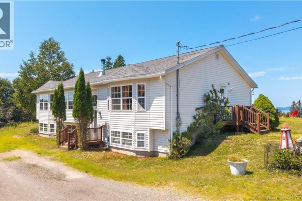Side view of a white house with vinyl siding and wooden deck stairs. - 65 Lambert Road, Lamberts Cove