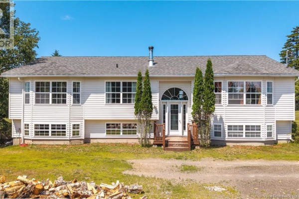 Front view of a white house with vinyl siding, arched glass front door, and large windows. - 65 Lambert Road, Lamberts Cove