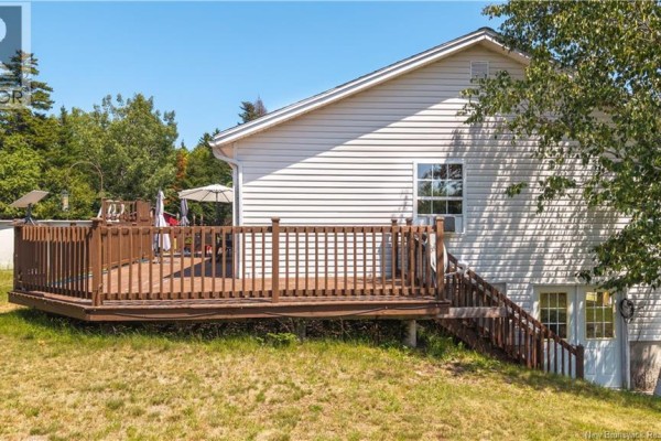 Back view of a white house with a large wooden deck and stairs leading down. - 65 Lambert Road, Lamberts Cove
