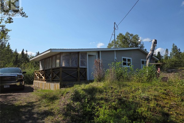 Side view of the cottage showing a porch with wooden railings and beige siding. - 68 Main Street, Charles Brook