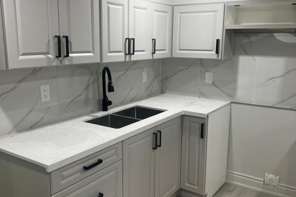 Kitchen corner with white countertops, light grey cabinets, and a double sink with a black faucet. - 68 Merton Road, Brampton