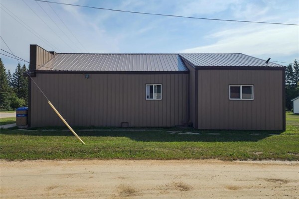 Side view of commercial building with brown metal siding and two small windows. - 68 Tache Street, Fisher Branch