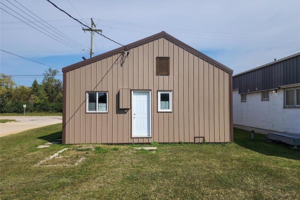Rear view of commercial building with brown metal siding, a door, and two windows. - 68 Tache Street, Fisher Branch
