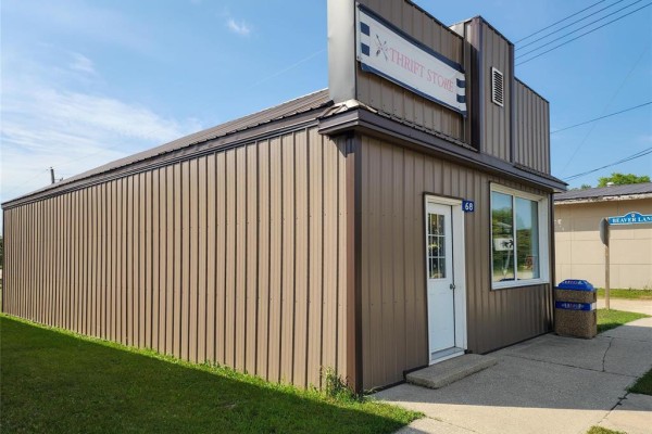 Angled exterior view of a small commercial building with brown siding and a thrift store sign. - 68 Tache Street, Fisher Branch
