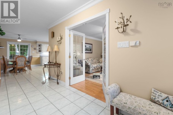 Interior view of a tiled hallway showing a dining area and glass doors to a living room. - 68 Two Rivers Drive, Mineville