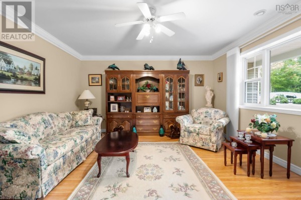 Living room with floral sofa, armchair, coffee table, built-in entertainment unit, and large window. - 68 Two Rivers Drive, Mineville