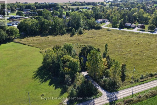 Aerial view of the property showing the house secluded by trees and bordering a country road and green fields. - 68 Victoria Street, Ashfield Colborne Wawanosh