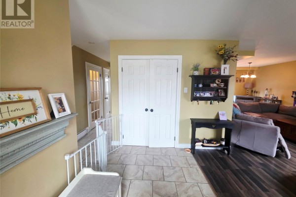 Interior view of an entranceway with beige walls, tile flooring, and a view into the living area. - 68 Whiteway Drive, Wabush