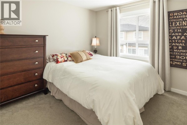 Open-concept layout showing living room and kitchen, with a cozy sectional and dining area in view. - 680 Old Meadows Road Unit# 81, Kelowna