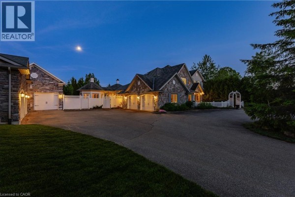 Stone house exterior with multiple garage doors at dusk, moon visible. - 6805 Concession Rd 2, Puslinch