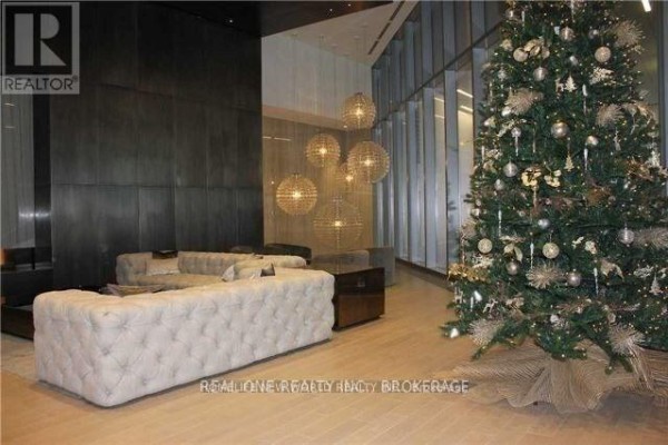 Lobby area with tufted sofas, decorative pendant lights, and a Christmas tree. - 6806 - 88 Harbour Street, Toronto