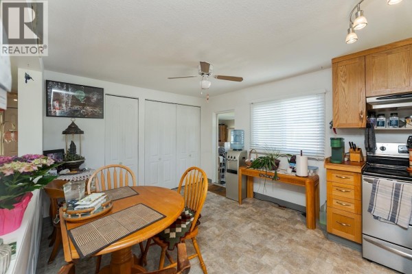 Backyard view with green grass, trees, and a mobile home. - 6815 Langer Crescent, Prince George