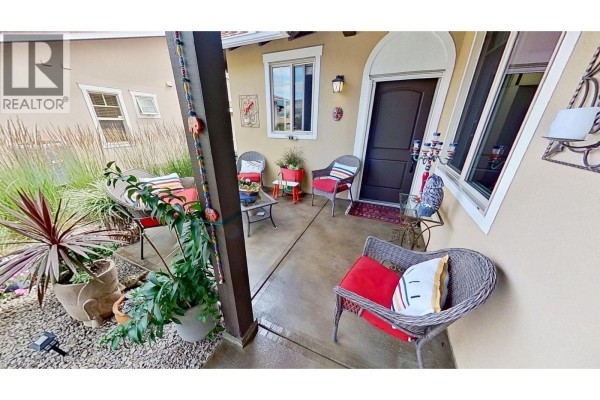 Covered front porch area with seating, plants, and a dark wood front door. - 6823 Tucelnuit Drive Unit# 80, Oliver