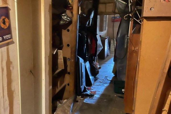 View through an open door into a narrow, cluttered hallway with items hanging on the wall. - 682419 260 Side Road, Melancthon