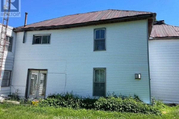Exterior of a white two-story house with a metal roof and double glass doors. - 682419 260 Side Road, Melancthon