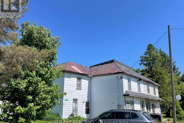 Side view of a white two-story house with a red metal roof and mature trees. - 682419 260 Side Road, Melancthon