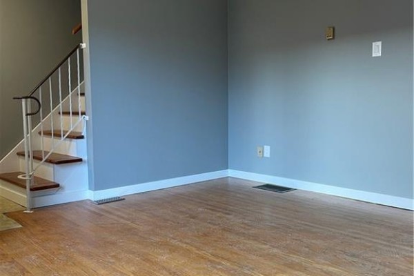 Empty room with wooden floors, grey walls, and a staircase on the left. - 683 Coronation Boulevard Unit# 2, Cambridge