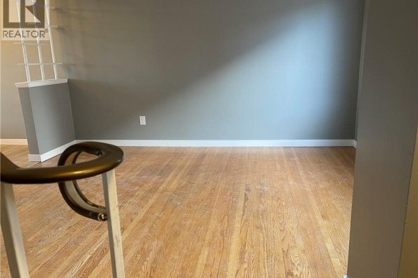 View of an empty room with wooden floors, grey walls, and a decorative partition. - 683 Coronation Boulevard Unit# 2, Cambridge