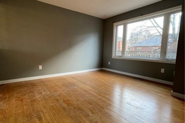 Room with wooden floors, grey walls, and a large bay window overlooking houses. - 683 Coronation Boulevard Unit# 2, Cambridge