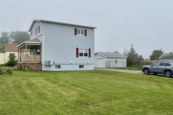 Side view of the house with a long driveway leading to the detached garage. - 683 Mahon Street, New Waterford