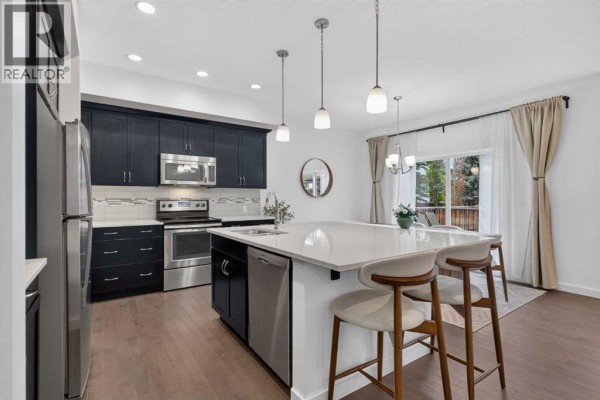Foyer with white walls, dark wood floors, and a white staircase. - 684 Evanston Drive Nw, Calgary