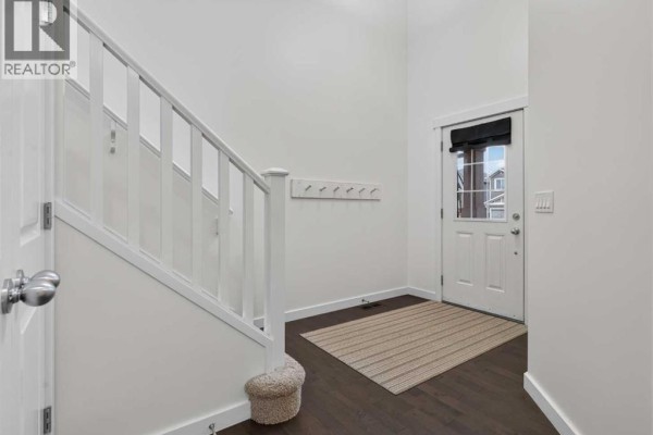 View into a hallway with a powder room and an adjacent kitchen with island seating. - 684 Evanston Drive Nw, Calgary