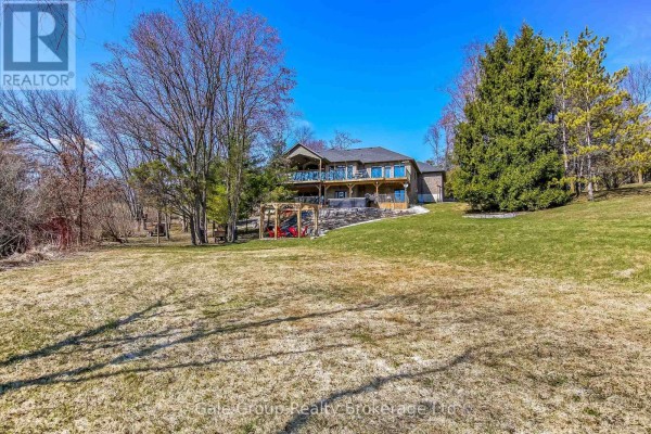 Rear exterior view of the house showcasing a large multi-level deck overlooking a grassy backyard. - 684744 Highway No 2 Highway, East Zorra Tavistock