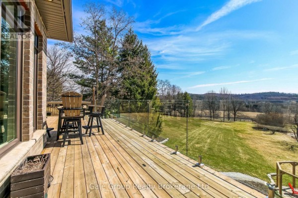 Wooden deck with glass railings offering expansive views of the surrounding countryside. - 684744 Highway No 2 Highway, East Zorra Tavistock