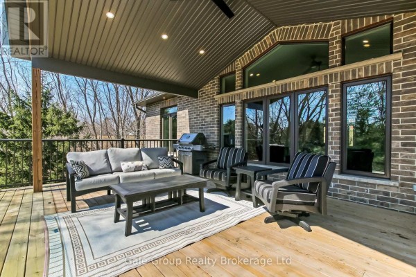 Covered outdoor living space with a sofa, chairs, coffee table, and barbecue on a wooden deck. - 684744 Highway No 2 Highway, East Zorra Tavistock