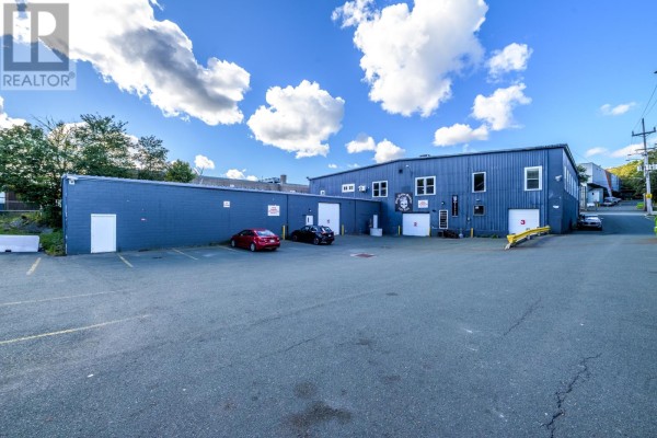 Room with wood laminate flooring, containing a black sofa, a small desk, and a black media stand. - 685-687 Water Street, St Johns
